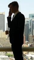 A Businessman Dressed in a Suit Using a Smartphone While Enjoying a View of the City Skyline video