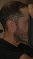 A focused man is diligently exercising in a gym environment, fully immersed in his workout routine video