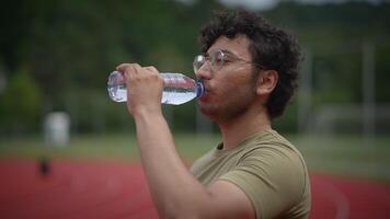 A Young Man is Hydrating on the Athletic Track After Completing His Intense Training Session video