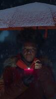 A person standing under an umbrella in snowy weather while using a mobile phone outside video