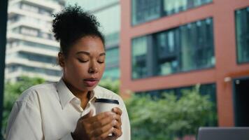 africano americano mujer mujer de negocios trabajando ordenador portátil al aire libre niña persona de libre dedicación empleado empresario hembra congelado congelación frío participación taza café bebida frío estremecimiento clima negocio frotamiento calle video