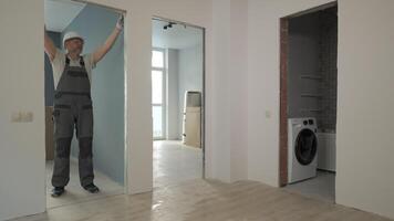 A builder in working uniform checks the size and quality of doorways in a new apartment. The concept of construction and repair. video