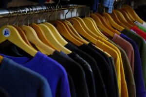 Thrifting's vibrant collection of sweaters, shirts, hoodies, trousers and knitted t-shirts are elegantly displayed on wooden hangers, featuring a variety of colors and textures. photo
