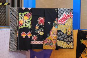 An array of Indonesian batik shirts and batik cloth hangs on the racks, displaying a variety of patterns and colors. photo