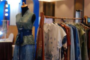 An array of Indonesian batik shirts and batik cloth hangs on the racks, displaying a variety of patterns and colors. photo
