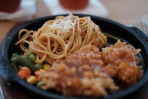 A delicious combination of crispy chicken and flavorful noodles served on a hot plate with vegetables. photo