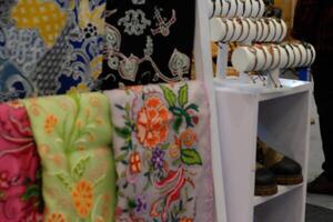 An array of Indonesian batik shirts and batik cloth hangs on the racks, displaying a variety of patterns and colors. photo