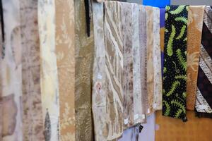 An array of Indonesian batik shirts and batik cloth hangs on the racks, displaying a variety of patterns and colors. photo