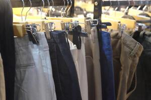 Thrifting's vibrant collection of sweaters, shirts, hoodies, trousers and knitted t-shirts are elegantly displayed on wooden hangers, featuring a variety of colors and textures. photo