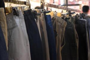 Thrifting's vibrant collection of sweaters, shirts, hoodies, trousers and knitted t-shirts are elegantly displayed on wooden hangers, featuring a variety of colors and textures. photo
