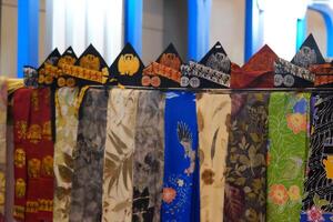 An array of Indonesian batik shirts and batik cloth hangs on the racks, displaying a variety of patterns and colors. photo