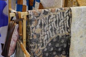 An array of Indonesian batik shirts and batik cloth hangs on the racks, displaying a variety of patterns and colors. photo