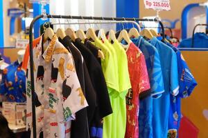 An array of Indonesian batik shirts and batik cloth hangs on the racks, displaying a variety of patterns and colors. photo