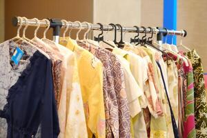 An array of Indonesian batik shirts and batik cloth hangs on the racks, displaying a variety of patterns and colors. photo
