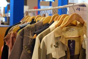 An array of Indonesian batik shirts and batik cloth hangs on the racks, displaying a variety of patterns and colors. photo