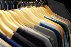 Thrifting's vibrant collection of sweaters, shirts, hoodies, trousers and knitted t-shirts are elegantly displayed on wooden hangers, featuring a variety of colors and textures. photo