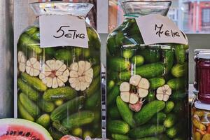Pickled cucumbers in jars with garlic at a farm market. photo