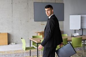 A determined businessman in a black suit confidently walks through the office, embodying professionalism and focus as he heads towards new challenges photo