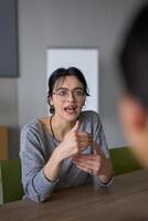 A close up portrait of a young businesswoman engaged in a professional meeting, confidently discussing ideas and strategies with her colleagues photo