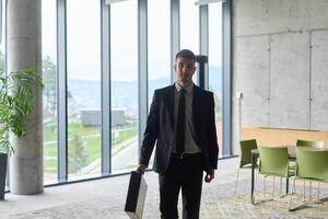A determined businessman in a black suit confidently walks through the office, embodying professionalism and focus as he heads towards new challenges photo