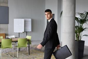 A determined businessman in a black suit confidently walks through the office, embodying professionalism and focus as he heads towards new challenges photo