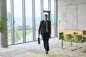 A determined businessman in a black suit confidently walks through the office, embodying professionalism and focus as he heads towards new challenges photo