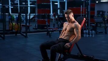 Young man flexing muscles. Athletic man doing exercises with dumbbell at biceps video