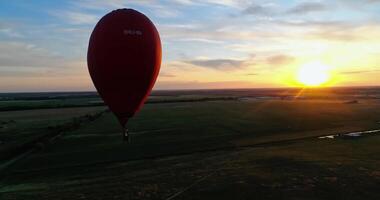 Landscape with hot air balloons flying over fields. Red hot air balloon in shape of heart over green field video