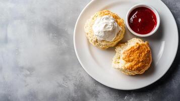 Scone sliced open on white plate with clotted cream, culinary photography photo