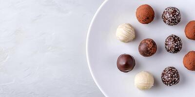 Chocolate truffles displayed in a row on a white plate, culinary photography photo
