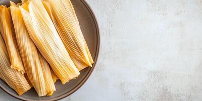 Plate of tamales with visible corn husks and a glimpse of the filling, arranged side by side, meal photography photo