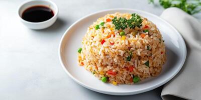 Fried rice placed on a white plate with garnish and soy sauce, food setting photo