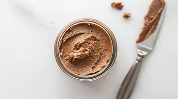 Glass jar of nut-free spread on a white background with a spreading knife, food photography photo