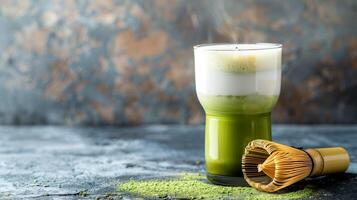 Glass of matcha latte with layers of green tea and milk next to a bamboo whisk, food photography photo