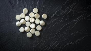 Unwrapped white mints arranged in a circular pattern on a dark surface, gastronomy photography photo