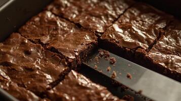 Knife cutting through a freshly baked pan of brownies, with crumbs visible on the surface, gastronomy photography photo