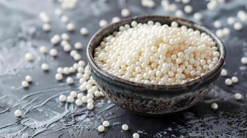 Small dish filled with white nonpareils, with some scattered around on a flat surface, gastronomy photography photo