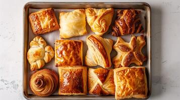 Tray of puff pastries showing a range of shapes and a consistent, flaky texture, photorealistic food photo