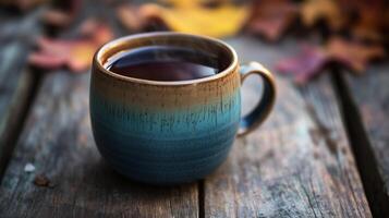 Ceramic mug filled with a dark, hot beverage, placed on a wooden table, food setting photo