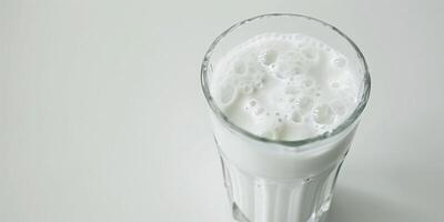 Glass filled with kefir, showing its slightly frothy surface, placed on a plain white background, food setting photo