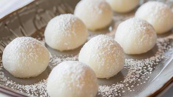 Small spherical mochi cakes coated with powdered sugar on a dish, meal photography photo