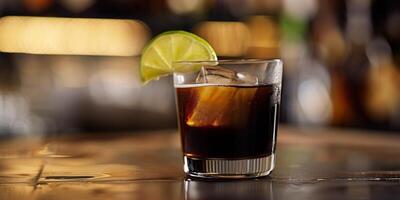 Short glass with a black liquid, a single ice cube, and a slice of lime, food setting photo