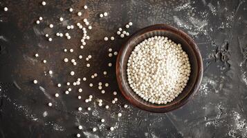Small dish filled with white nonpareils, with some scattered around on a flat surface, meal photography photo