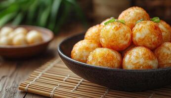 A bowl of fried food with a green leaf on top. The bowl is full of small, golden balls photo