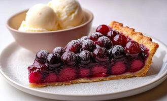 A slice of cherry pie sits on a plate next to a bowl of ice cream. The pie is covered in powdered sugar and looks delicious photo