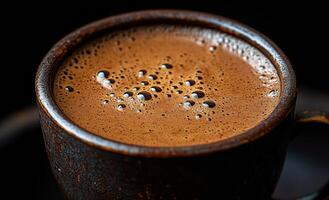 A cup of coffee with foam on top. The foam is bubbly and the coffee is brown photo