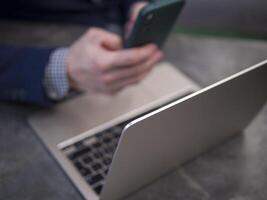 Businessman multitasking in modern office, using smartphone and laptop to manage tasks and communication. Businessman demonstrates efficiency Businessman working remotely, using smartphone and laptop photo