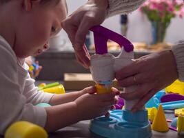 Mother and toddler are enjoying quality time together, engaging in creative play with vibrant modeling clay ice cream set, fostering imagination and fine motor skills Concept teaching children skills photo