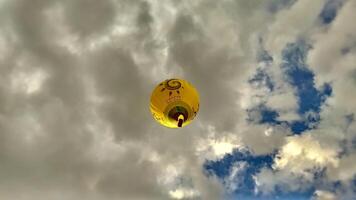 04 June 2020, Vilnius, Lithuania - Yellow Gariunai Hot Air Balloon flying up in the cloudy sky bottom up view photo