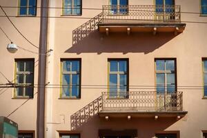 An old balconies casting shadows on brown building in old town with many wires over the road on this street photo